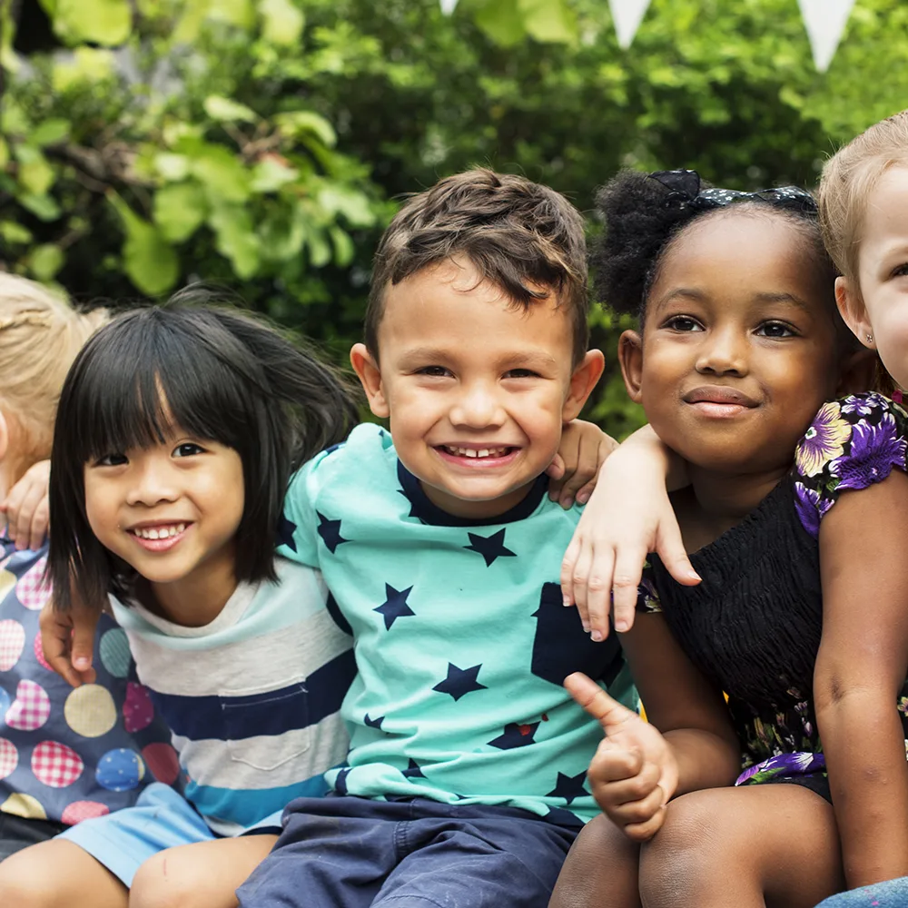 A group of children smiling outside of a Red Balloon Child Care Center daycare