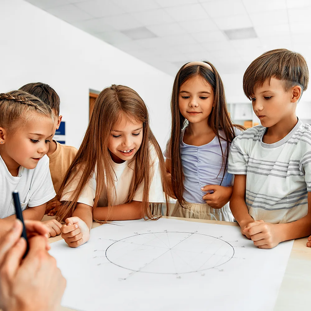 5 children standing around a drawing at a table at Red Balloon Child Care Center daycare