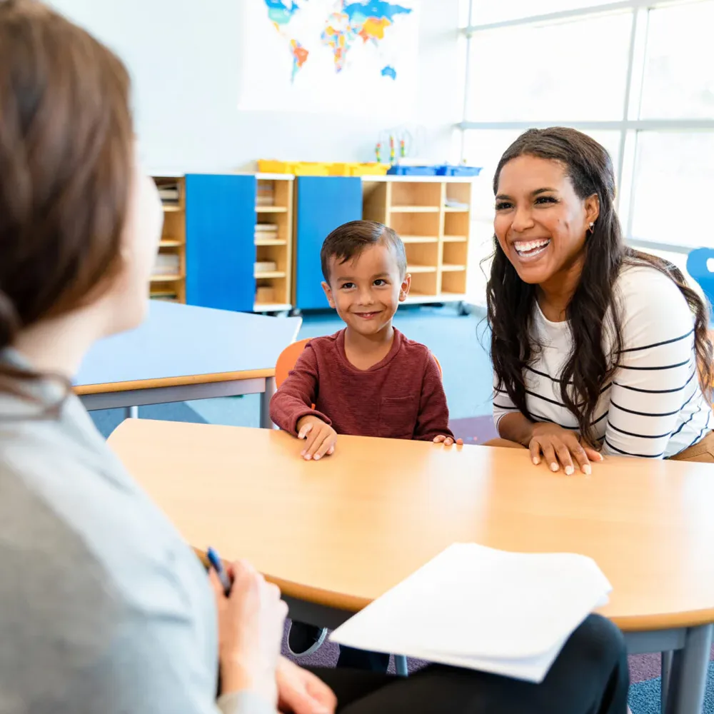 A child and an adult at a table in a Red Balloon Child Care Center daycare