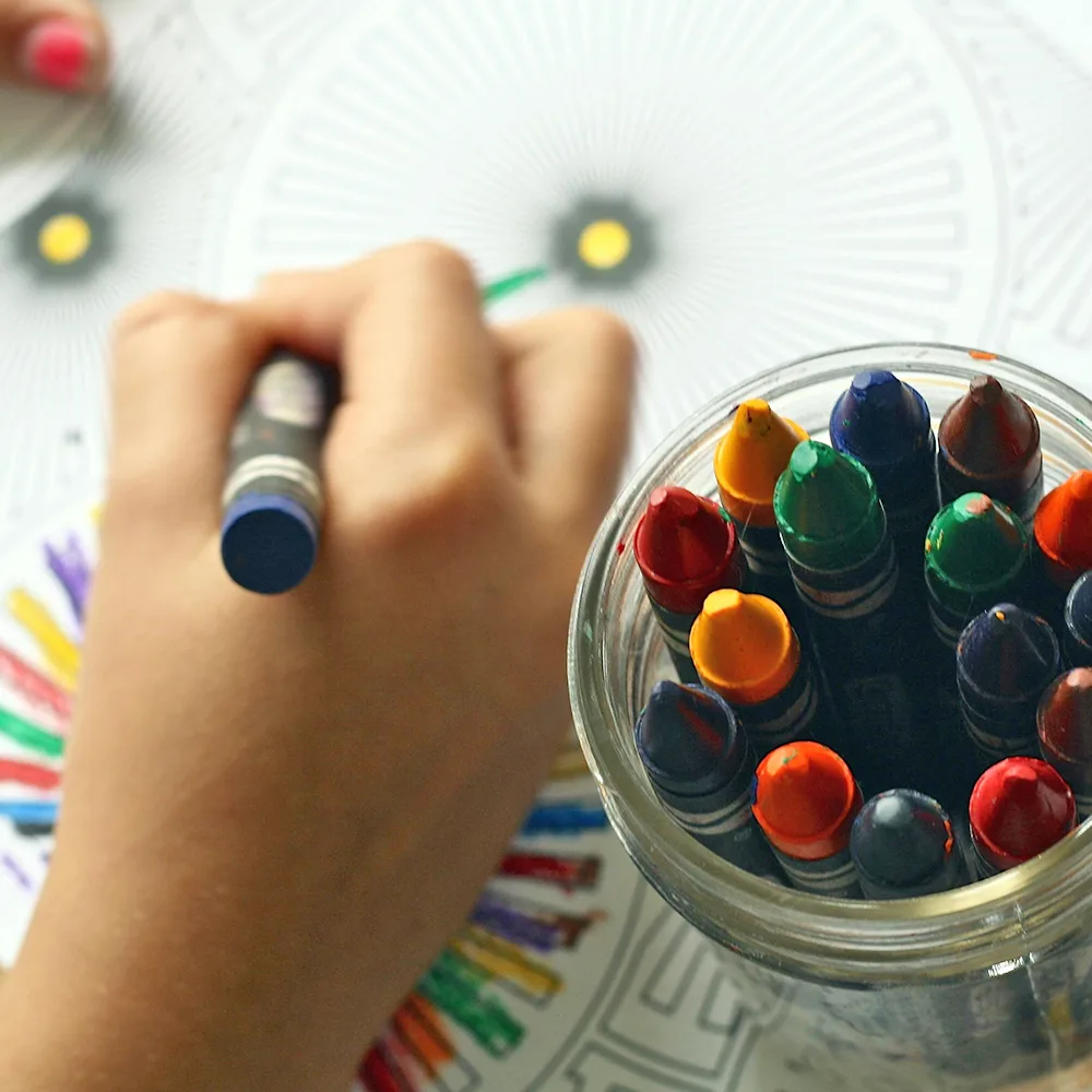 A child using a blue crayon to color a wheel at a Red Balloon Child Care Center daycare