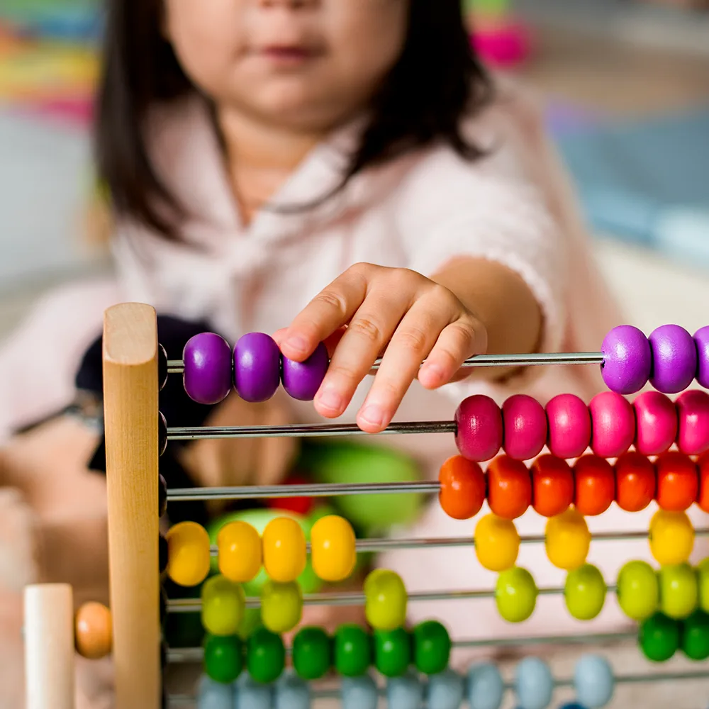 A child working with beads on an abacus at Red Balloon Child Care Center daycare