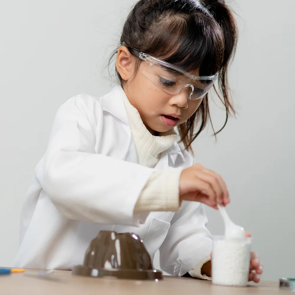 A young child using a spoon during a science experiment at Red Balloon Child Care Center daycare