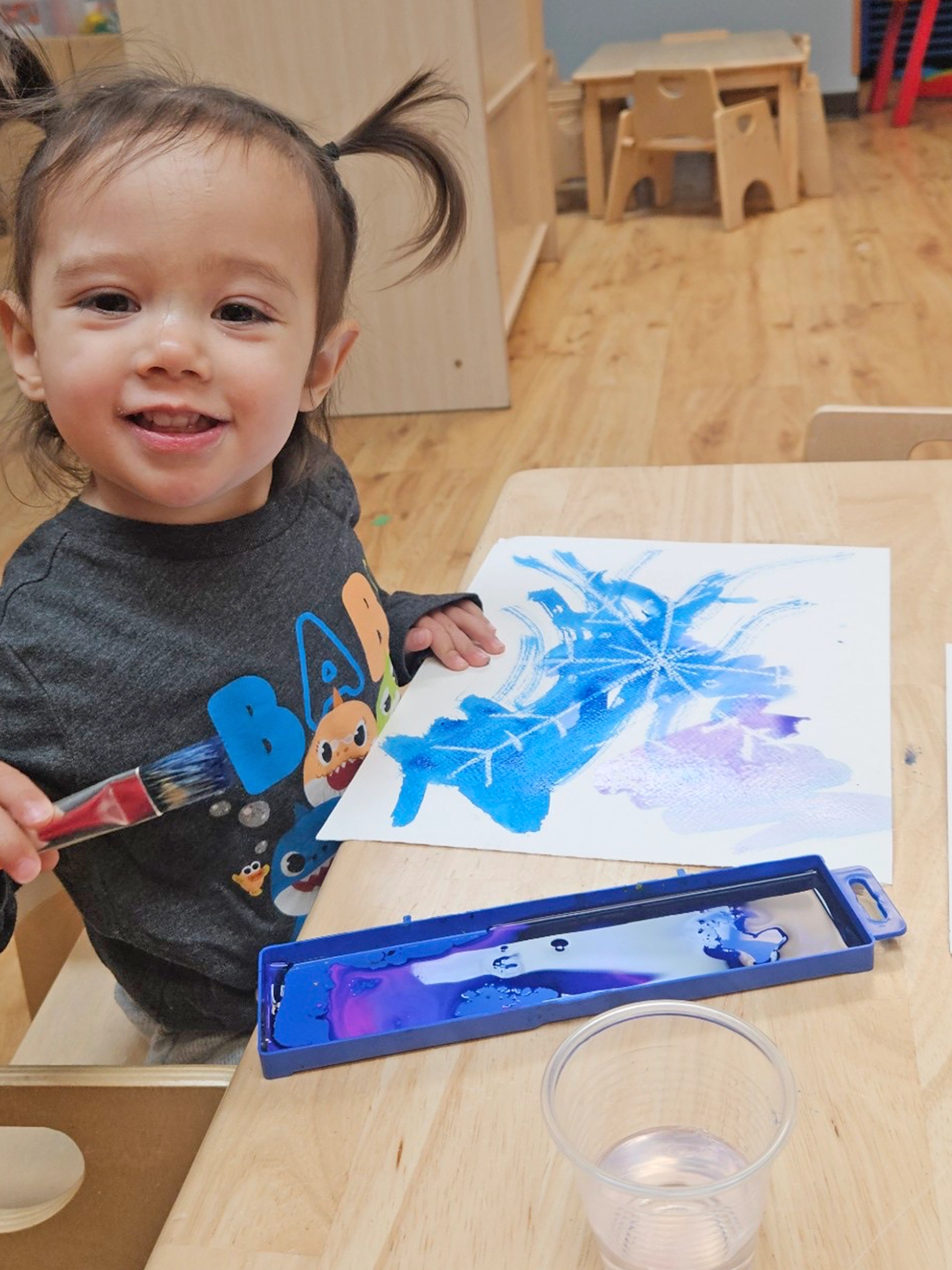 Child coloring with blue crayon at a Red Balloon Child Care Center daycare.