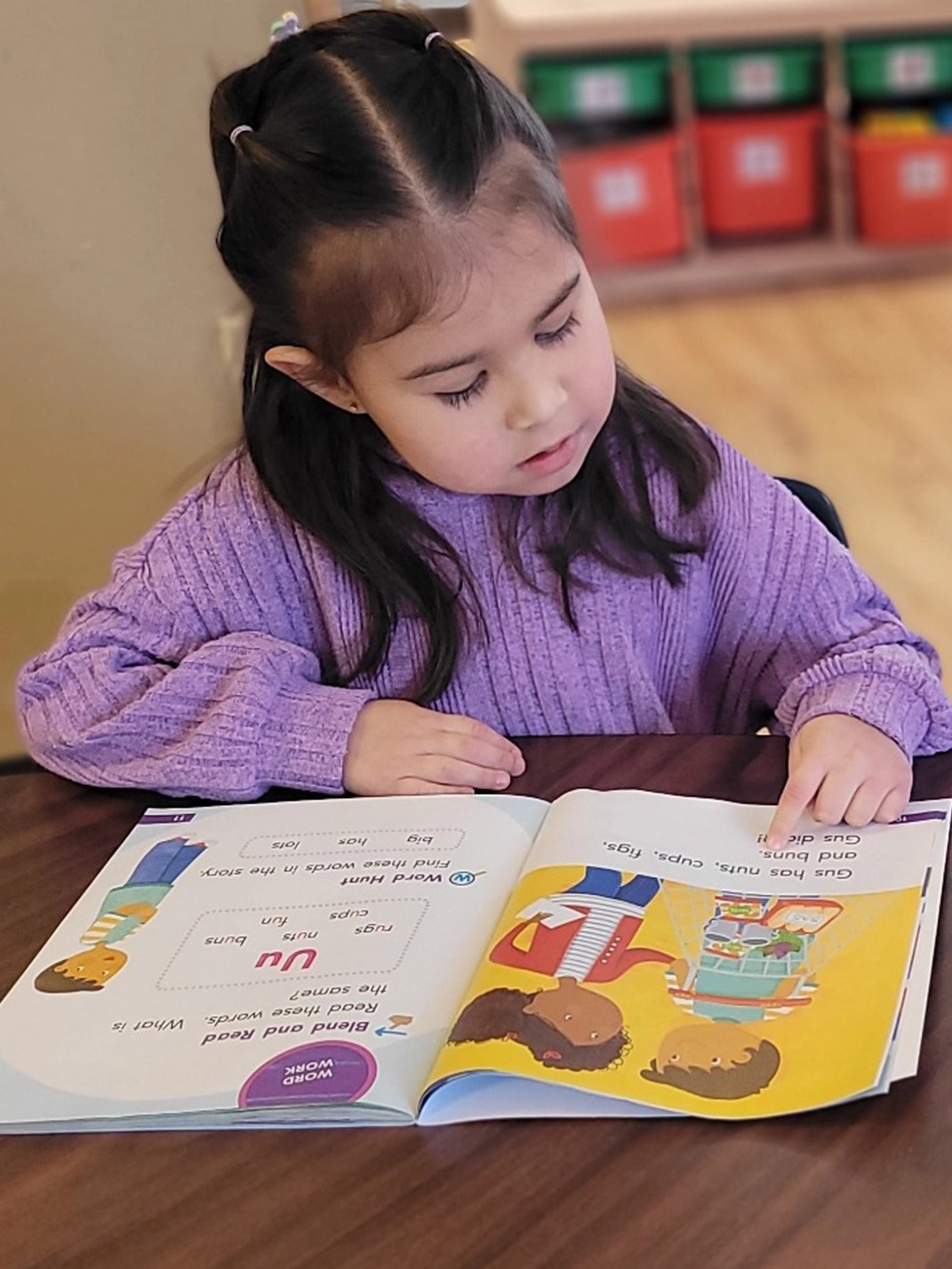 A child in purple reading a book at Red Balloon Child Care Center daycare.