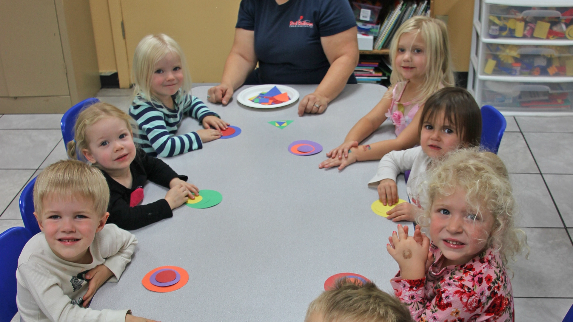 A table full of children working on crafts at a Red Balloon Child Care Center daycare