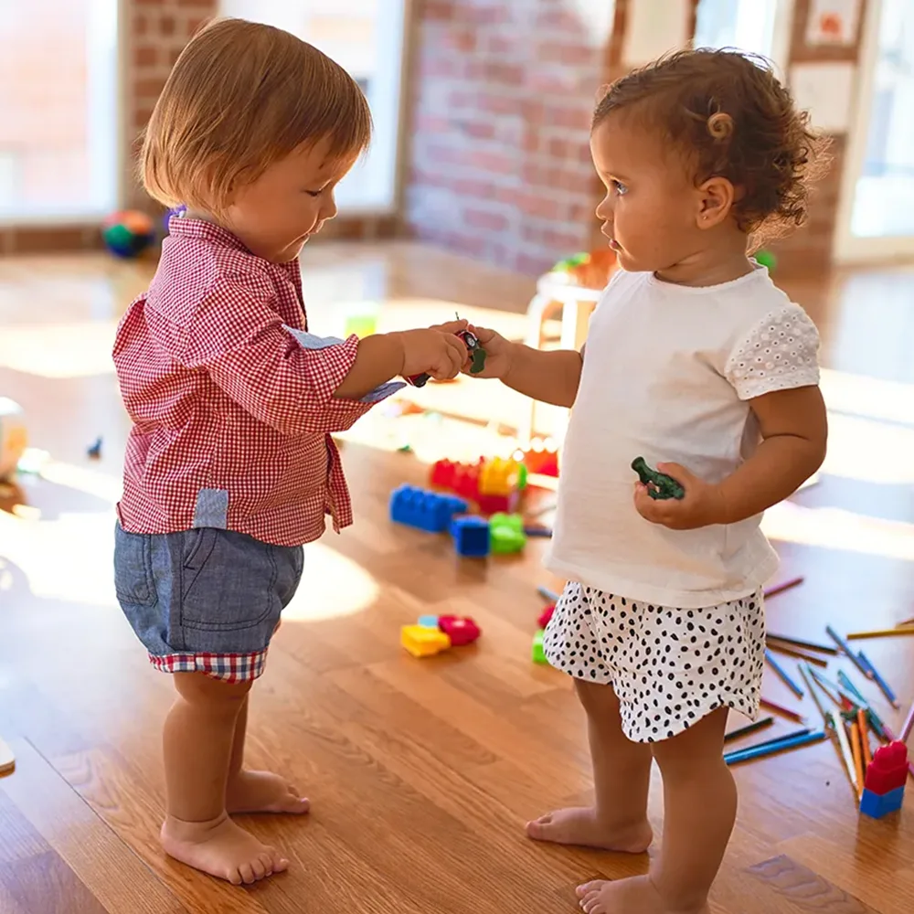 Two toddlers sharing toys at a Red Balloon Child Care Center daycare