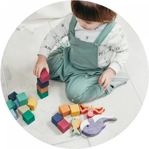 A child playing with blocks on the floor at a Red Balloon Child Care Center daycare